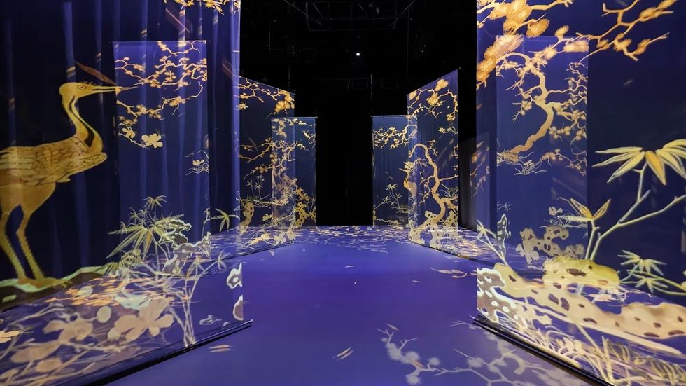 Illuminated panels with golden crane and floral designs on a dark blue background.