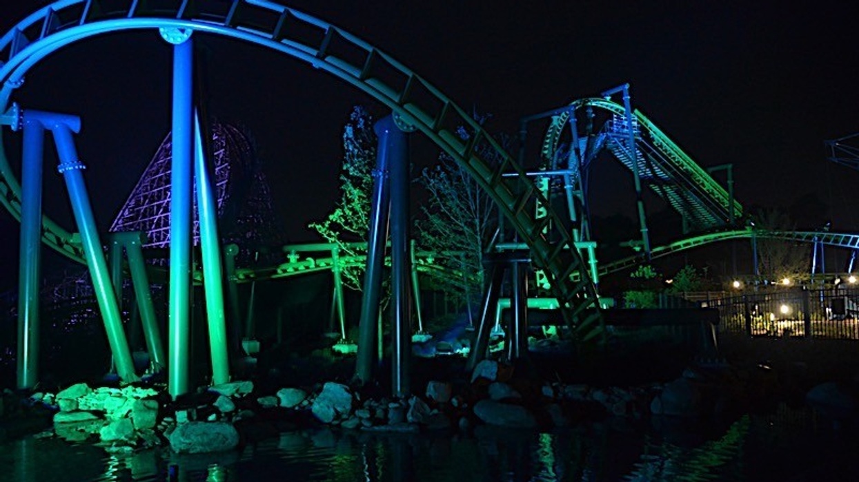 Illuminated roller coaster with blue and green lights at night.