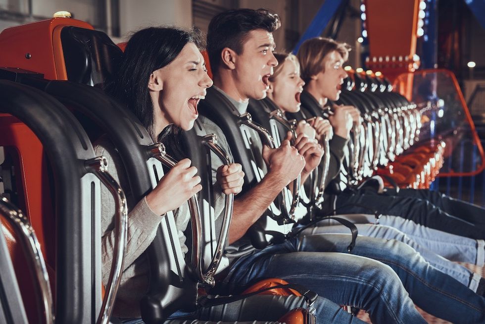 Image of shocked excited four friends sitting on carousel in amusement park.