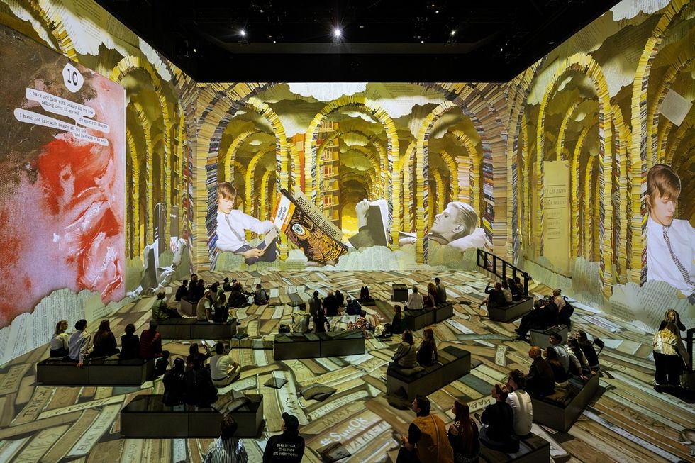Immersive art installation with book-themed projections and seated audience.