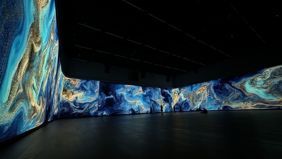 Immersive digital installation with swirling blue and gold patterns on walls.