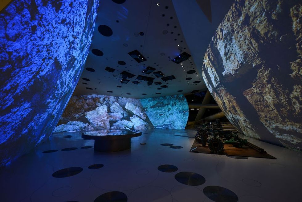 Immersive room at National Museum of Qatar with rocky textures projected on curved walls.