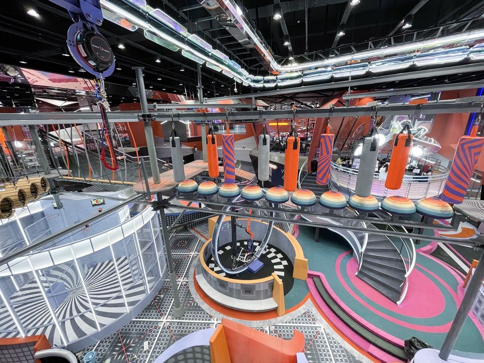Indoor adventure course with colorful obstacles and spiral staircases.