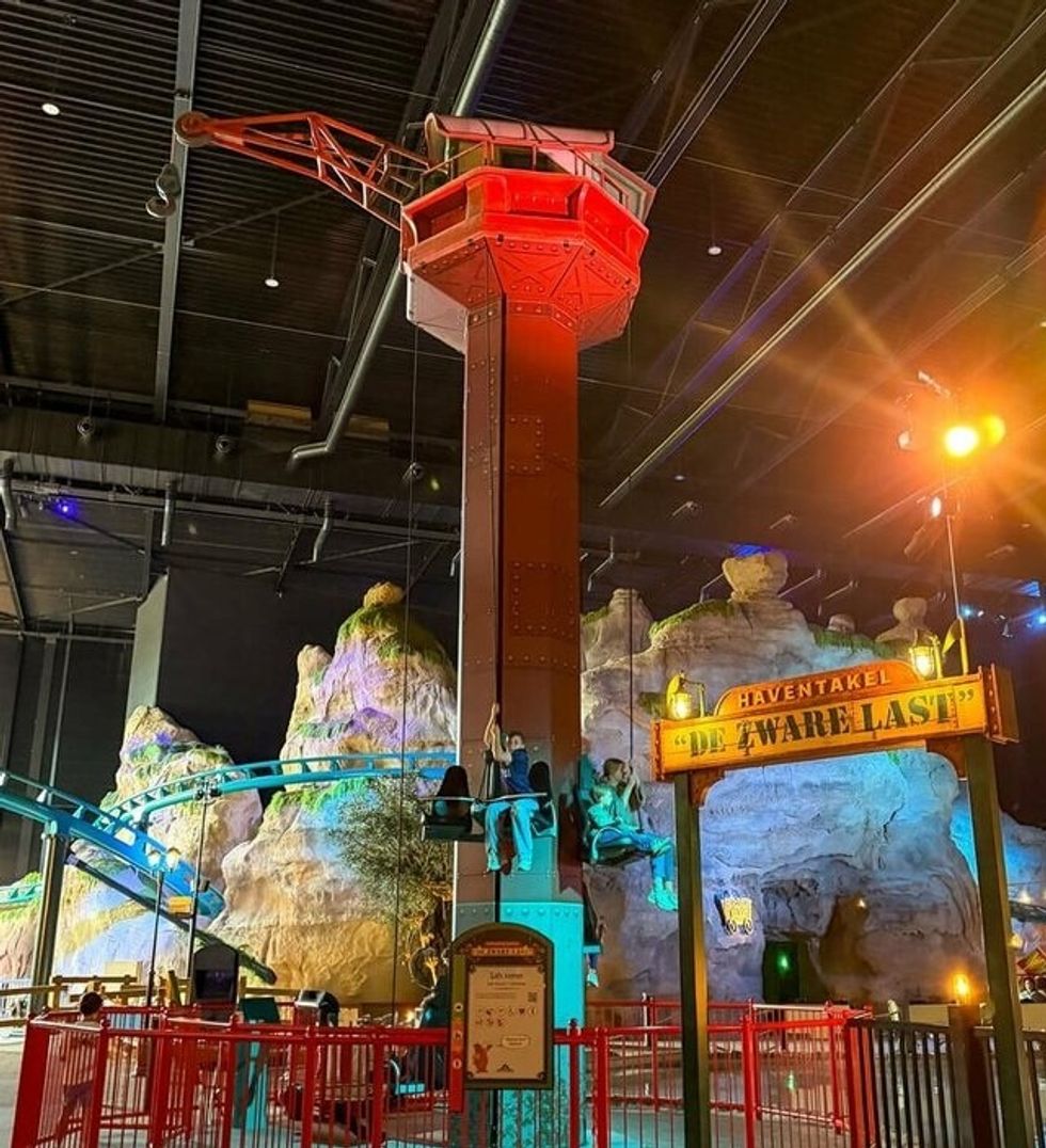 Indoor amusement ride, De Zware Last at Bommelwereld, with crane theme, rocky backdrop, and red lighting.