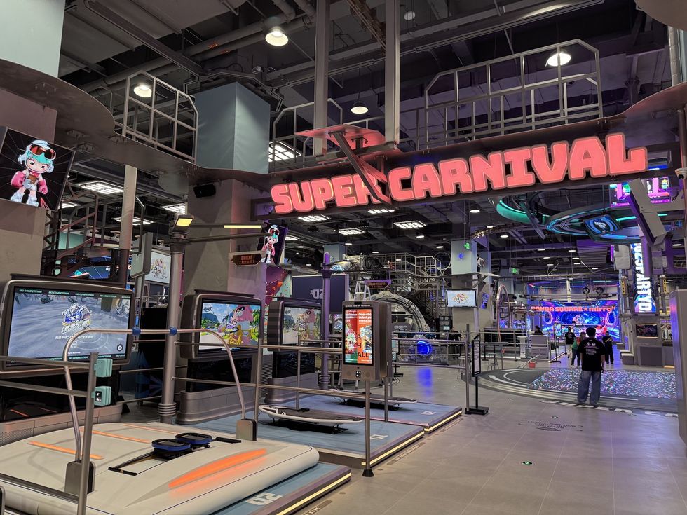 Indoor arcade scene with glowing "SUPERCARNIVAL" sign and gaming stations.