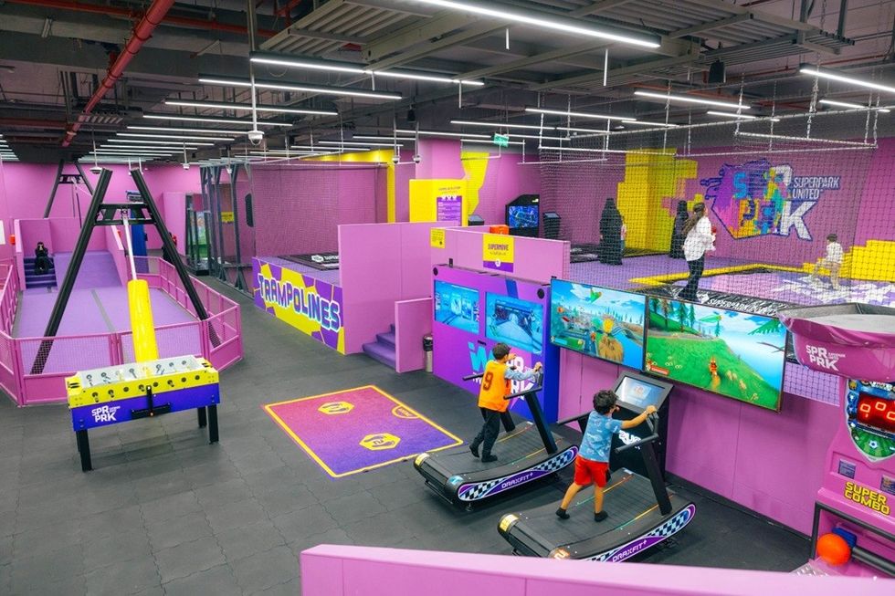 Indoor arcade with pink walls, trampolines, and interactive games for children.