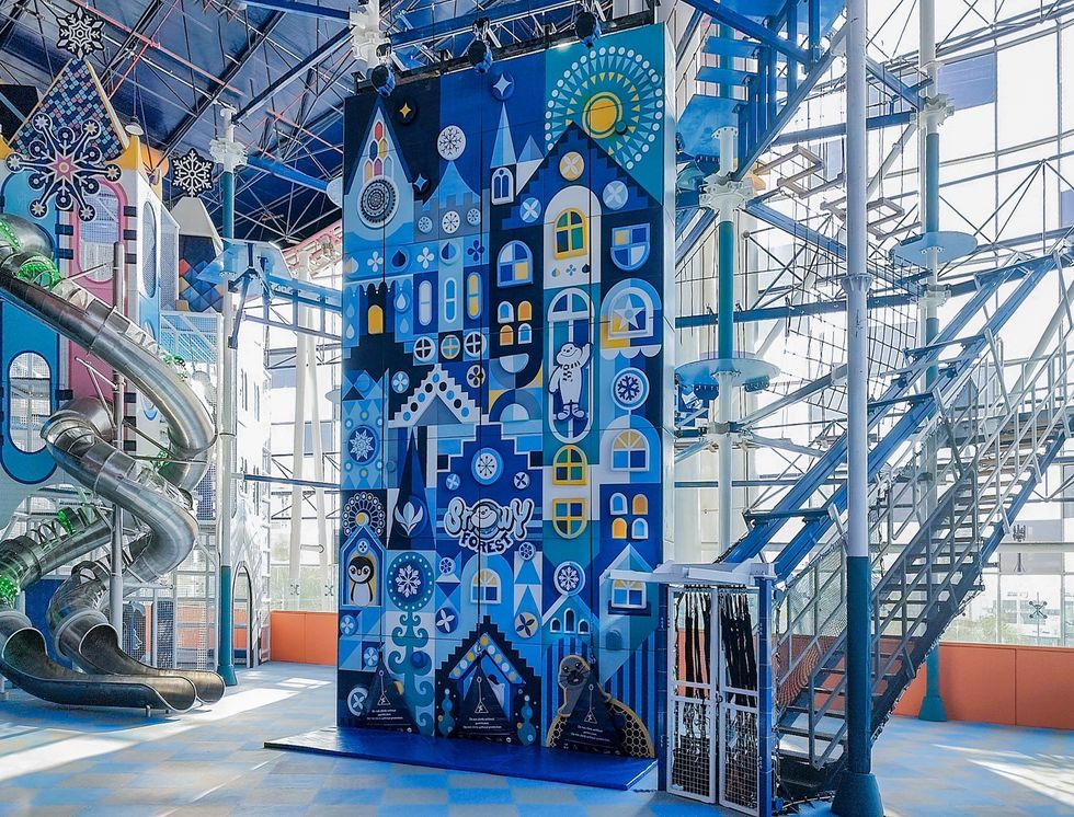 Indoor climbing wall with colorful geometric designs and adjoining slides.