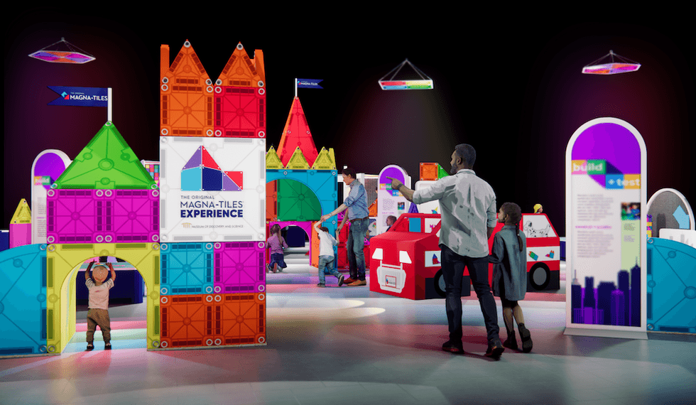 Indoor exhibit with colorful Magna-Tiles structures and children exploring the display.