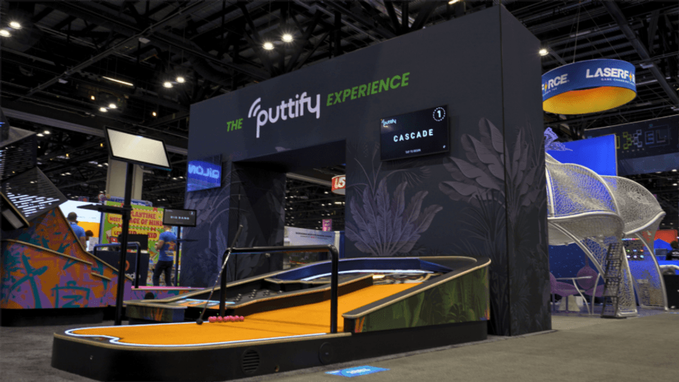 Indoor mini-golf setup titled "The Puttify Experience" at an exhibition hall.