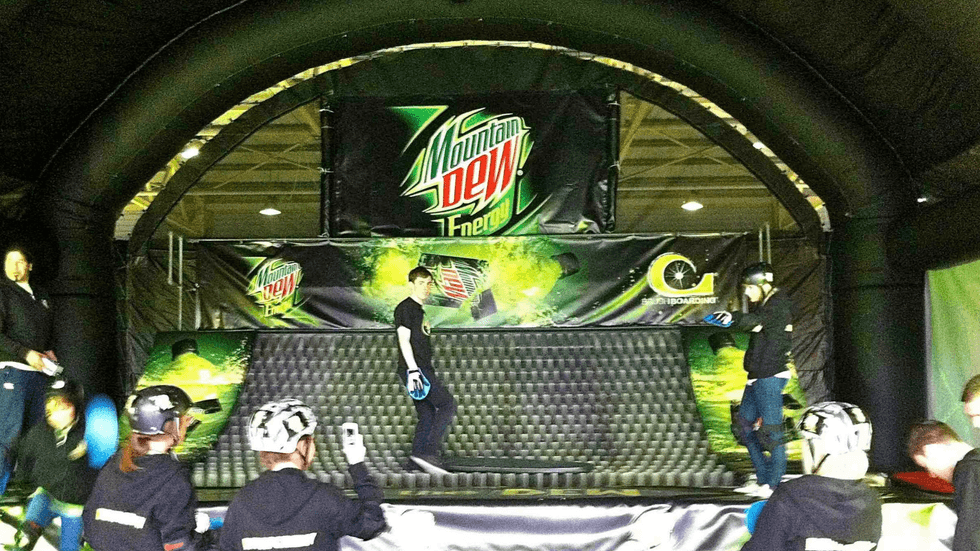 Indoor Mountain Dew skateboarding demo with participants in helmets.