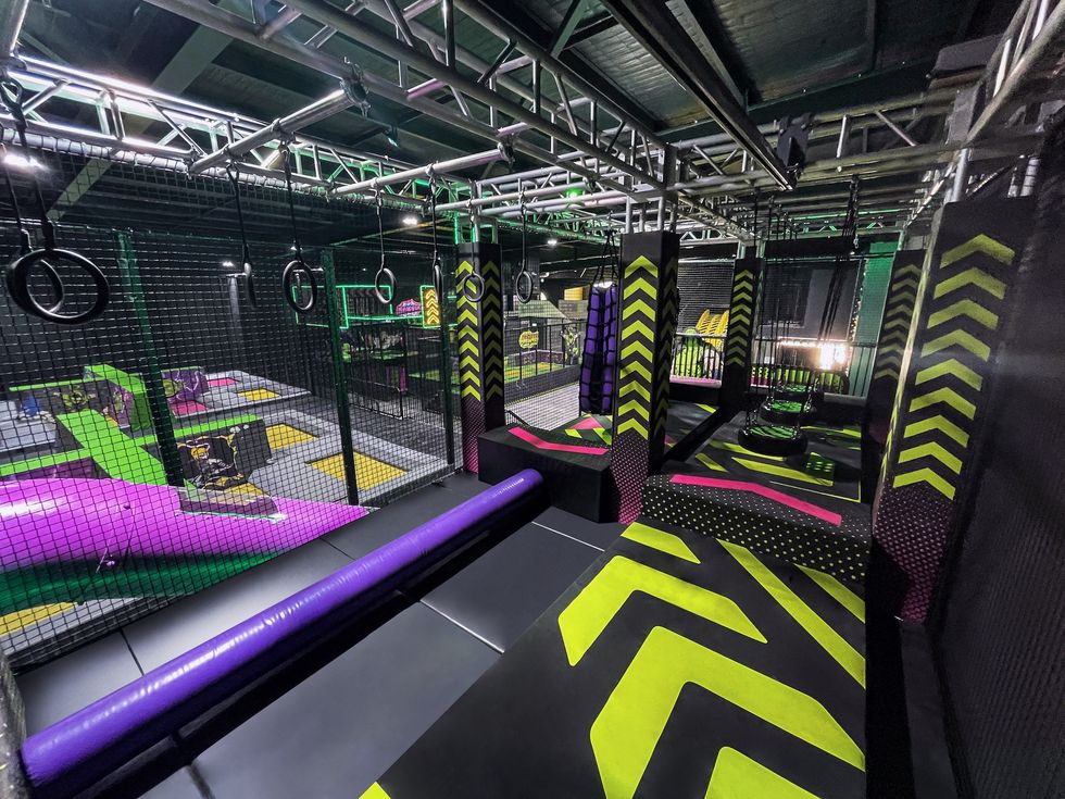 Indoor obstacle course with neon colors and various climbing structures.
