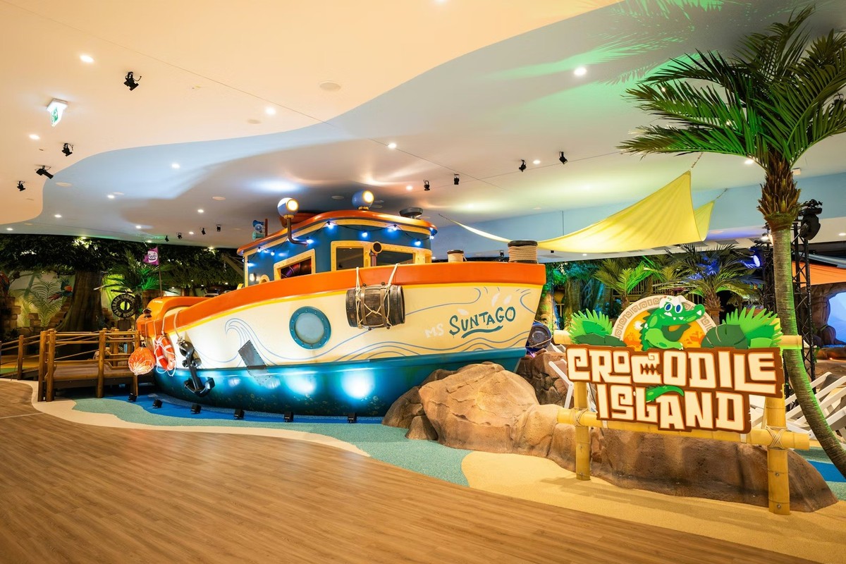 Indoor play area with a boat and "Crocodile Island" sign surrounded by tropical decor. Creative Studio Berlin