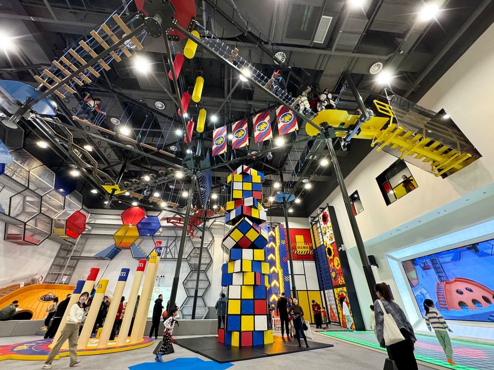 Indoor playground with climbing structures and colorful geometric designs.