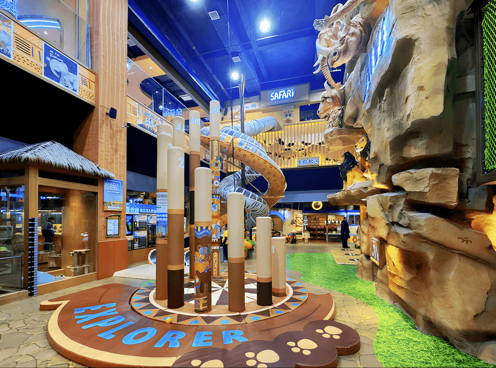 Indoor playground with safari theme, spiral slide, and animal sculptures.