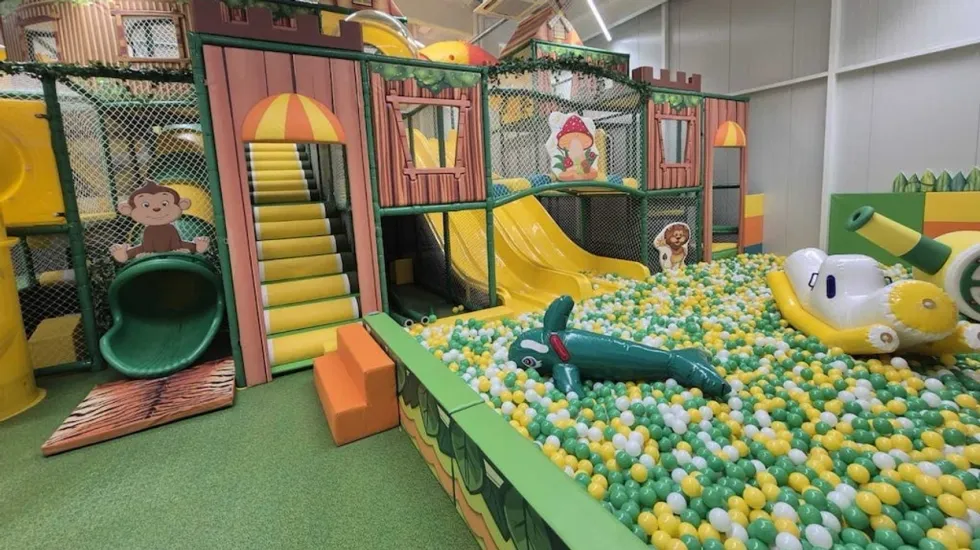 Indoor playground with slides, ball pit, jungle theme, and playful decorations.