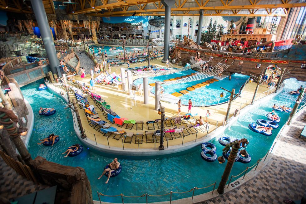 Indoor water park, Rulantica, with pools, lazy river, slides, and colorful lounge chairs.