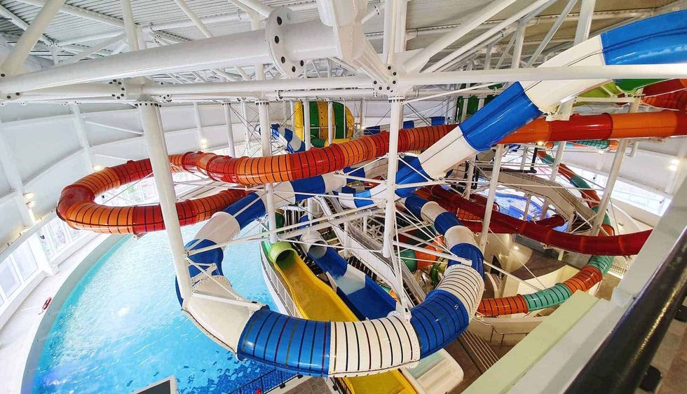 Indoor water park with colorful twisting slides above a pool.