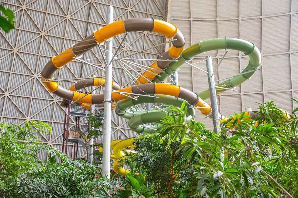 Indoor water slide spirals above tropical plants in a large, domed structure at Tropical Islands