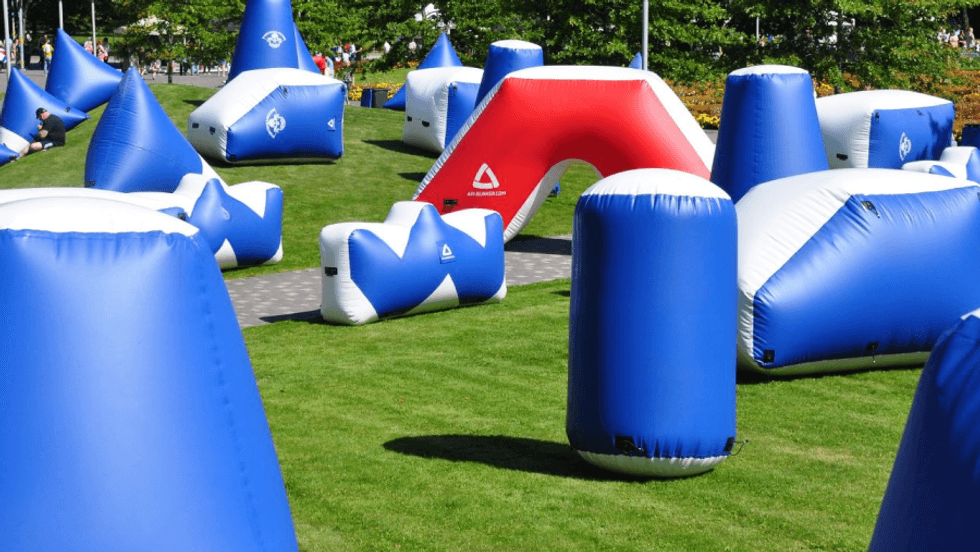 Inflatable paintball barriers on a green grass field.
