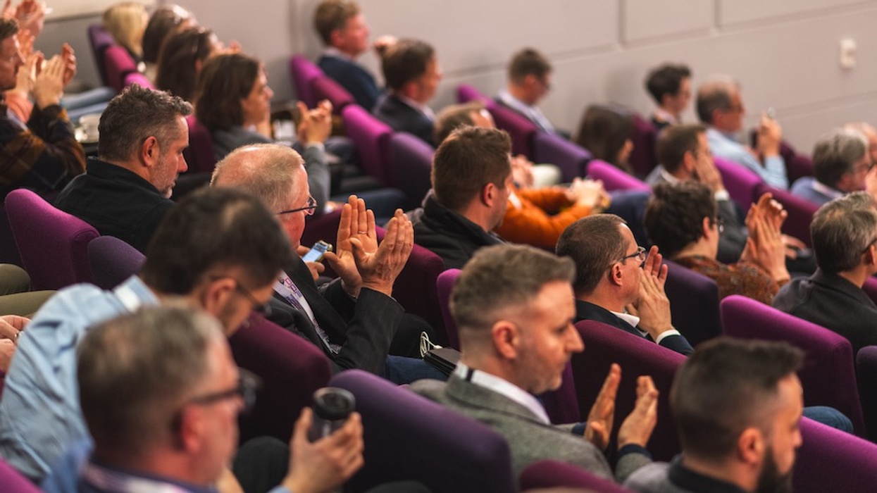 InnovateX 2025 audience clapping in a conference hall with purple seats.
