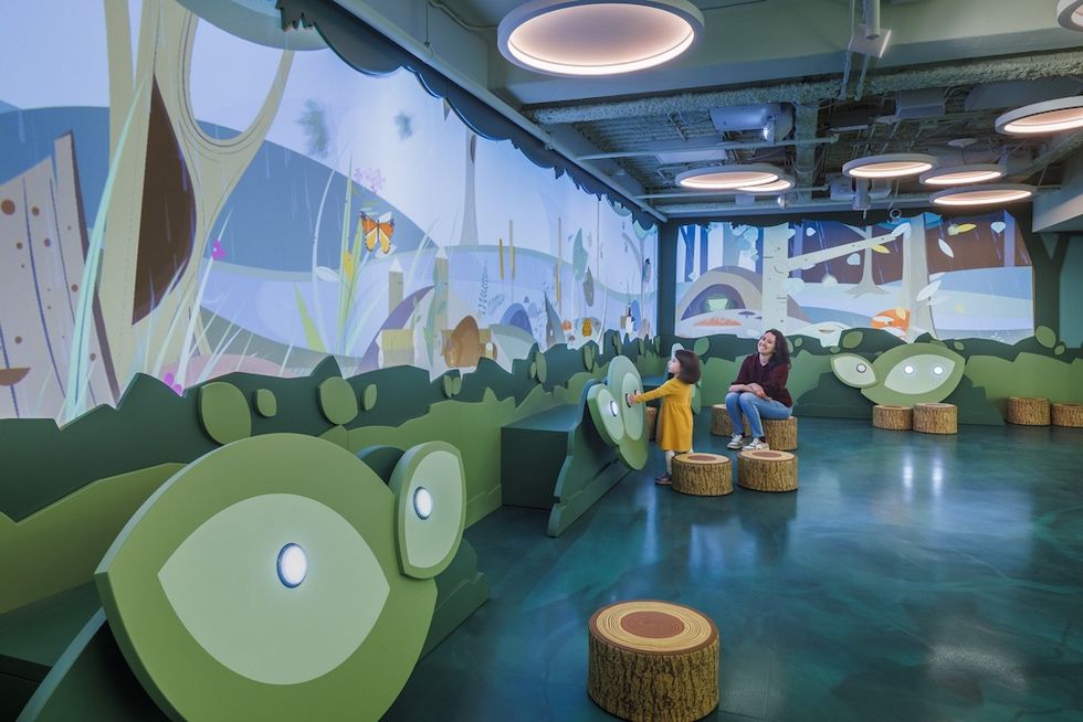 Interactive children\u2019s play area with nature-themed wall projections and circular seating at Discovery World on Market