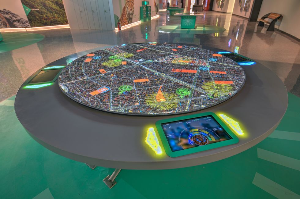 Interactive digital map table with illuminated screens in a modern exhibition space.