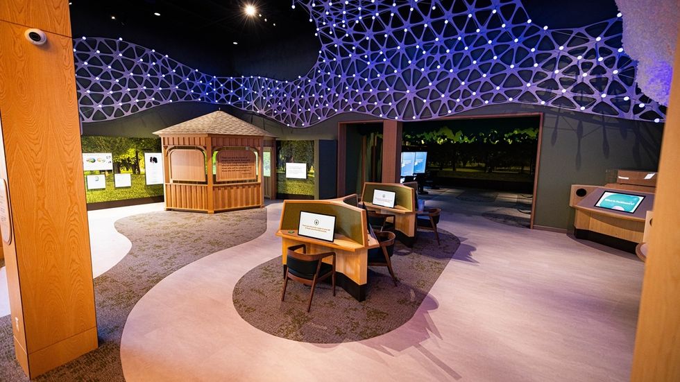 Interactive exhibit at the Marlin and Doris Thomas Memory Center with touchscreen stations and illuminated lattice ceiling.