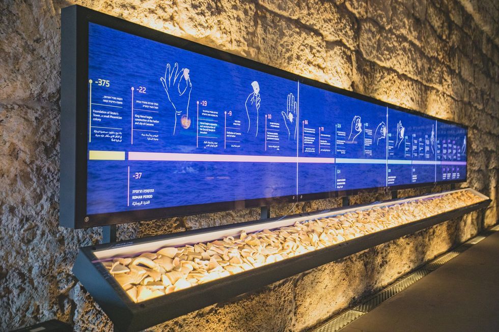 Interactive museum timeline display with artifacts in front and stone wall background.