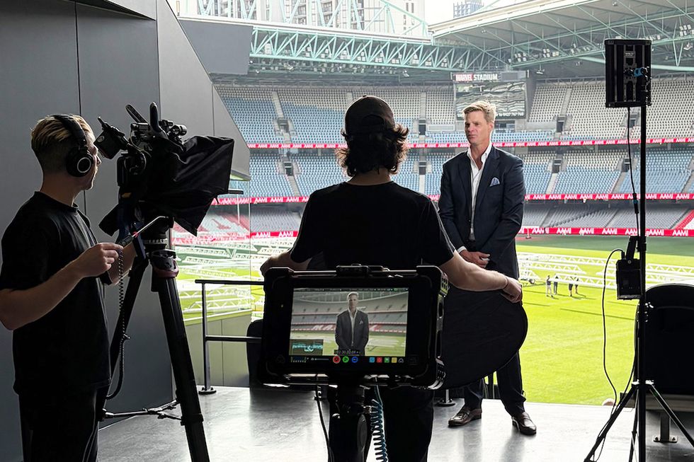 Interview setup at a stadium with a camera crew and a person being filmed.