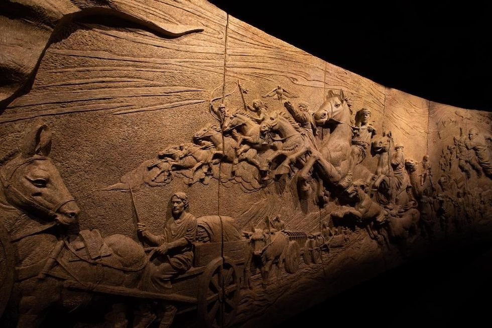 Intricate carved stone mural inside Alif \u2013 The Mobility Pavilion.