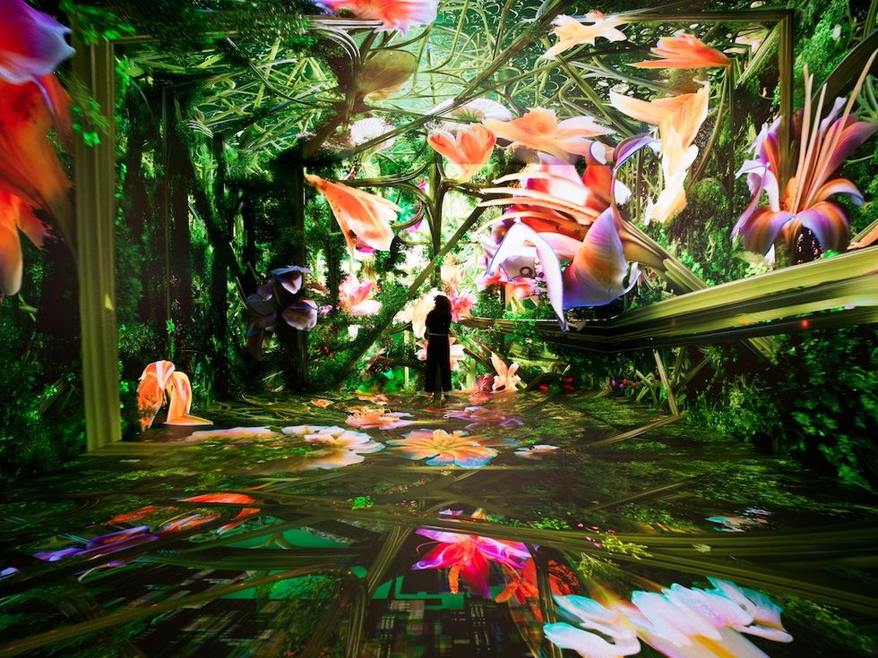 Intricate digital art installation at Dataland with vivid flowers and greenery surrounding a lone figure.