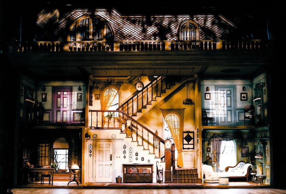 Intricate dollhouse set design with stairs, multiple rooms, and detailed furnishings.