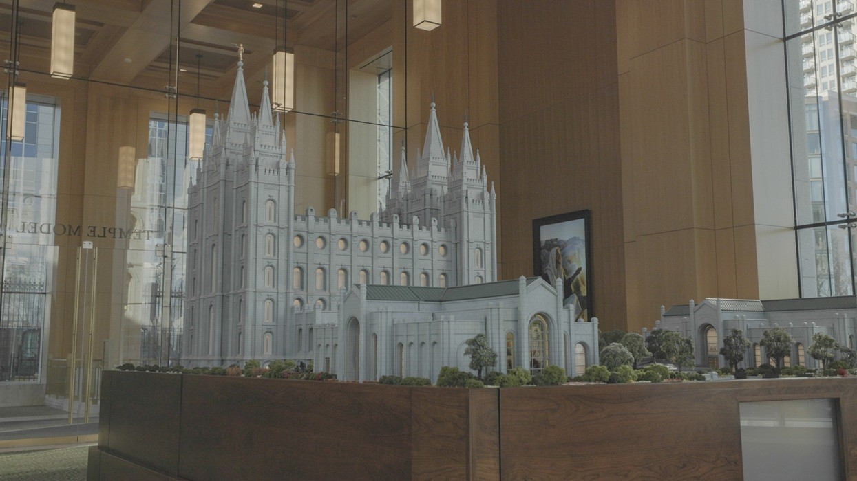 Intricate temple model displayed in a modern glass-walled room.