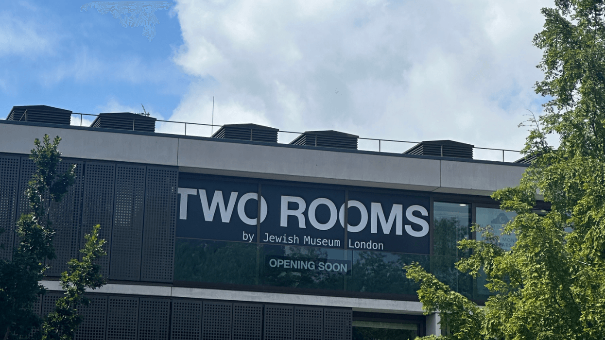 Jewish Museum London building sign, 'Two Rooms, Opening Soon,' surrounded by trees.