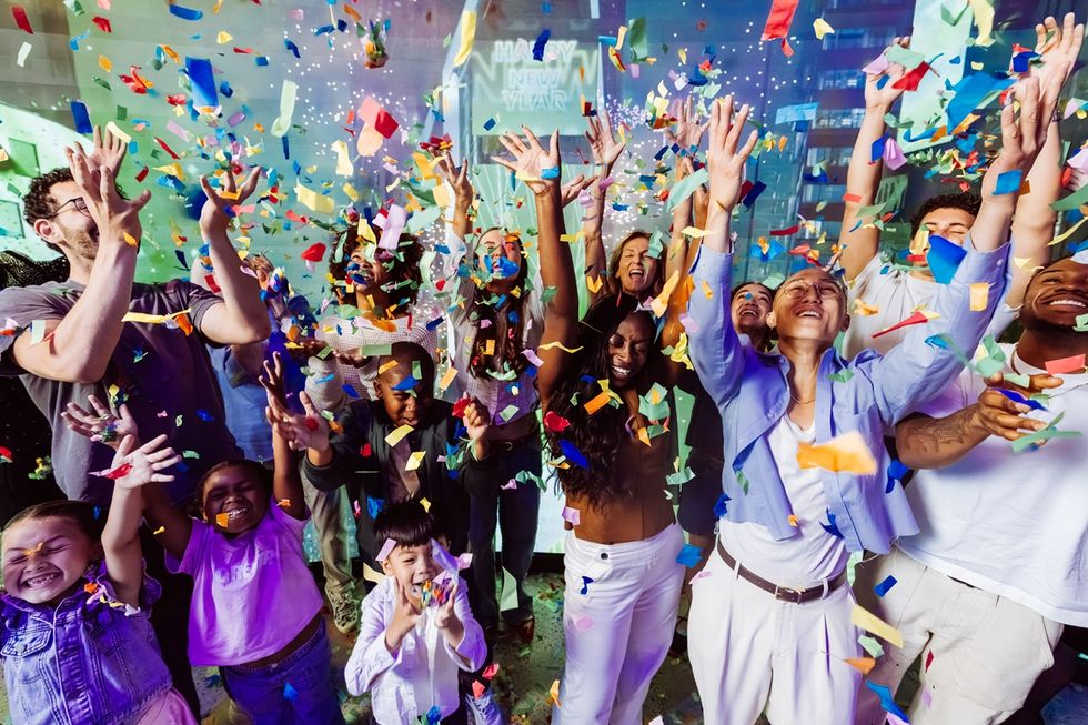 Joyful crowd celebrating with colorful confetti indoors in the Times Travel experience.