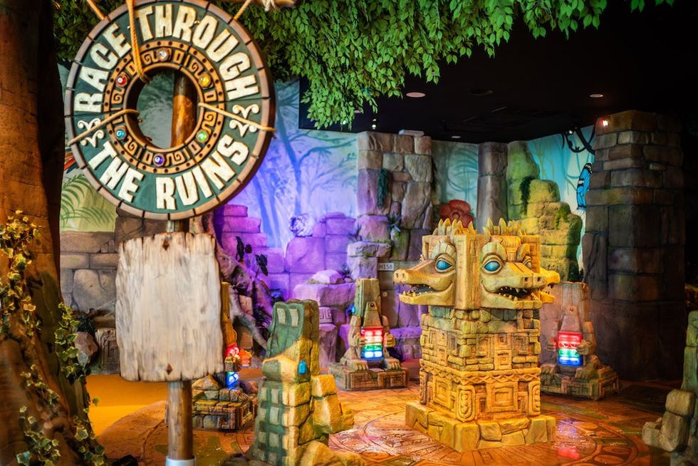 Jungle-themed indoor game area with stone idols and 'Race Through the Ruins' sign at Suntago Water World.