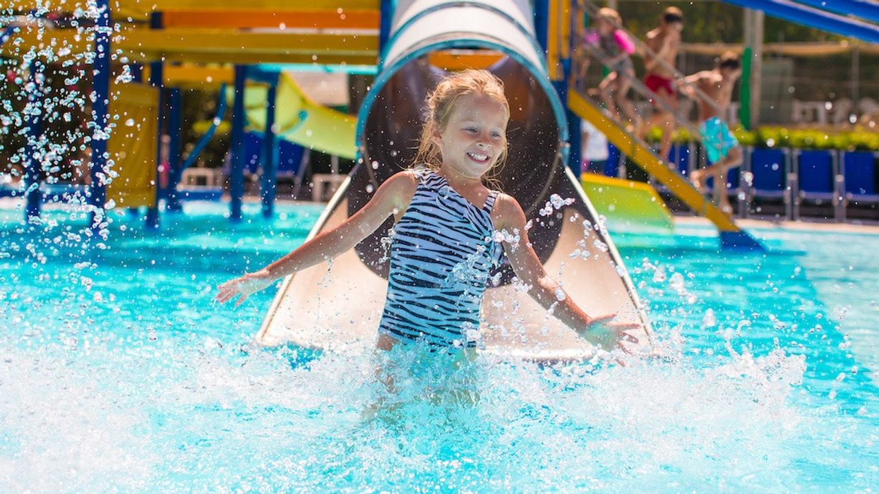 Kid on water slide at aquapark at summer holiday