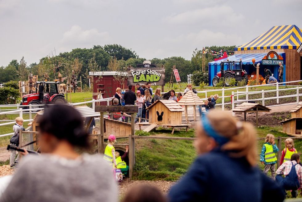 Kids and families enjoying Faret Shaun Land at Skanes Djurpark with tractors and playhouses.