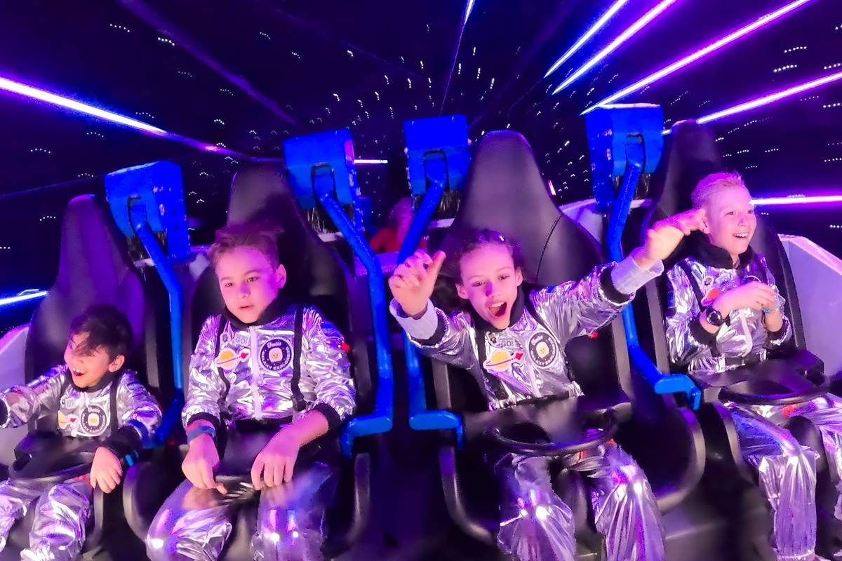 Kids in silver spacesuits enjoying a vivid, neon-lit space ride - legoland's galacticoaster