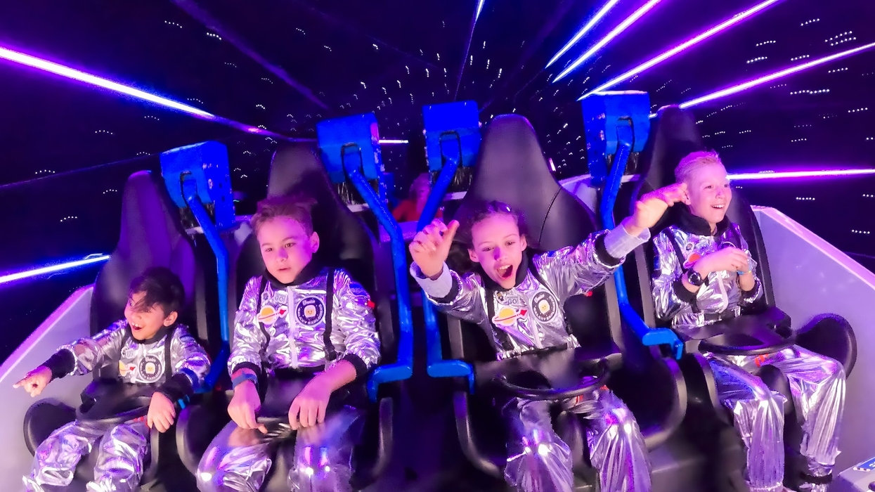 Kids in silver spacesuits enjoying a vivid, neon-lit space ride - legoland's galacticoaster