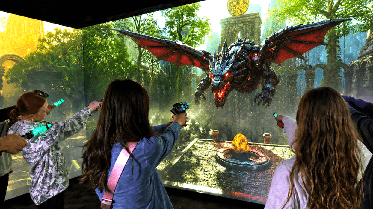 Kids playing a VR dragon game, aiming controllers at a screen with a flying dragon.