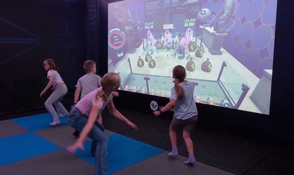 Kids playing an interactive video game, jumping on a padded floor.