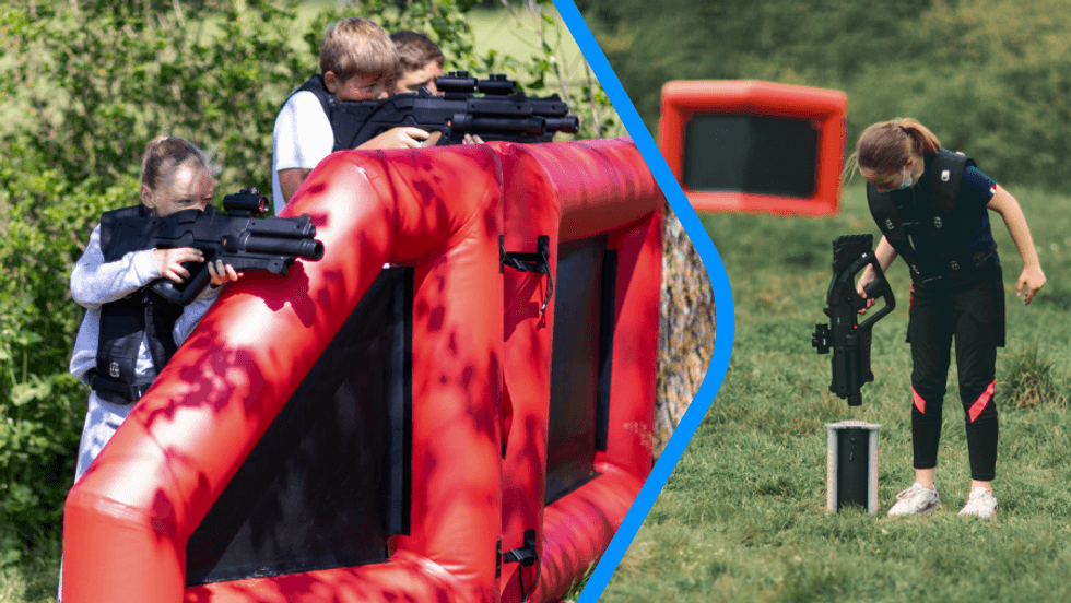 Kids playing laser tag outdoors behind inflatable barriers.