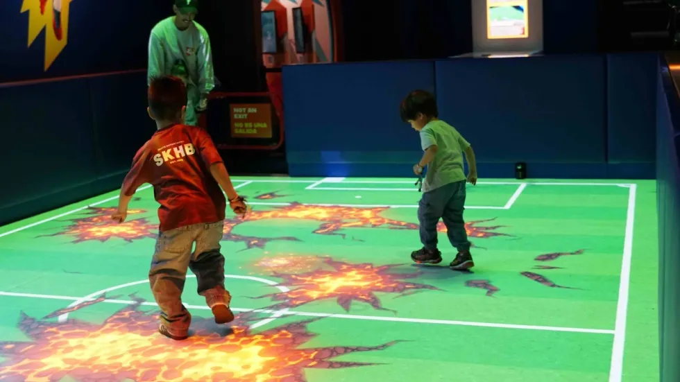 Kids playing on a digital, interactive football pitch at Perot Museum for Soccer: More Than a Game