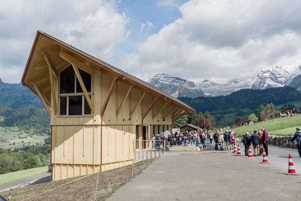 Klanghaus and Peter Roth Resonance Centre - a wooden building on a hillside with people and scenic mountain background.
