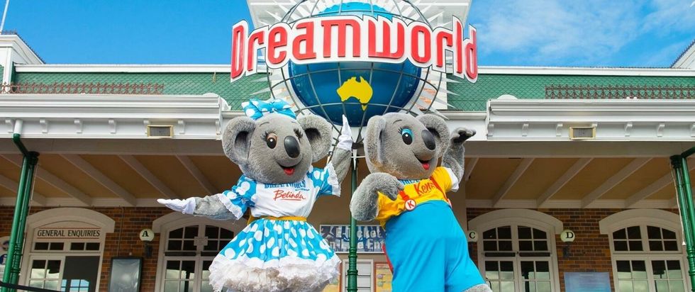 Koala mascots dance joyfully in front of Dreamworld entrance.