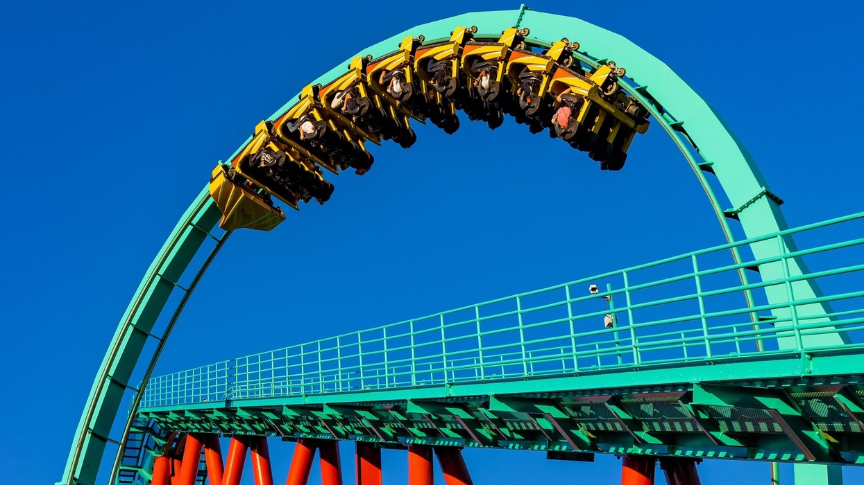 Kumba roller coaster on a loop against a clear blue sky.