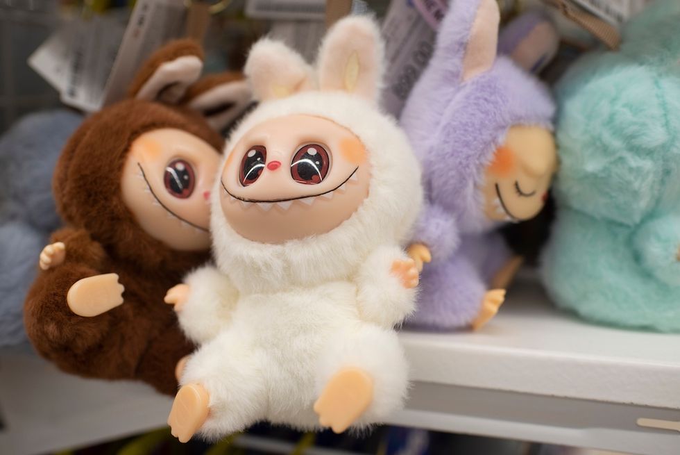 Labubus - plush toys with wide eyes and toothy smiles, dressed as bunnies, on a store shelf.