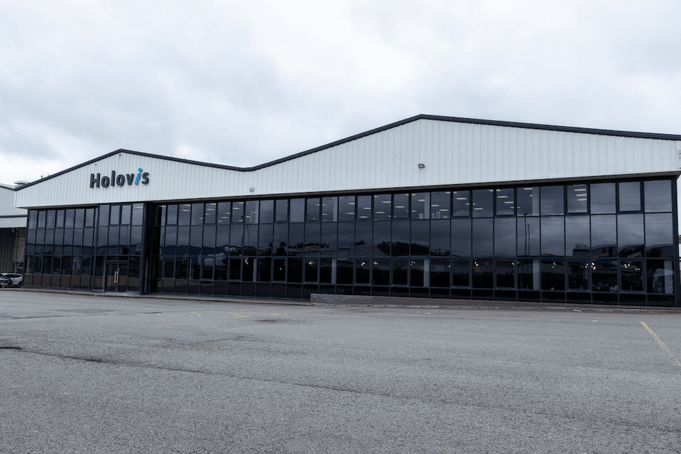 Large building with "Holovis" sign and glass facade under cloudy sky.