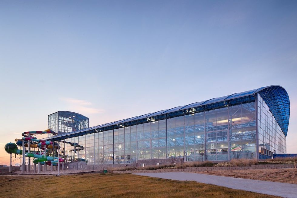 Large glass building with colorful water slides, set against a twilight sky.
